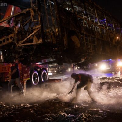 Les pompiers enlèvent la carcasse d'un bus incendié par les émeutiers à Hammanskraal