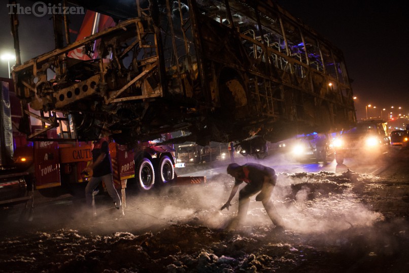 Les pompiers enlèvent la carcasse d'un bus incendié par les émeutiers à Hammanskraal