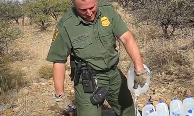 Policier détruisant un stock d'eau laissé par les humanitaires