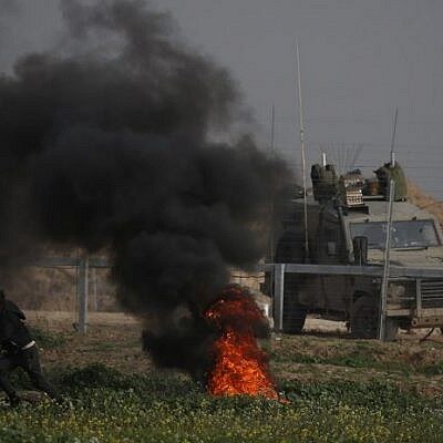 Manifestants palestiniens et blindé israélien de part et d'autre de la clôture hier vendredi