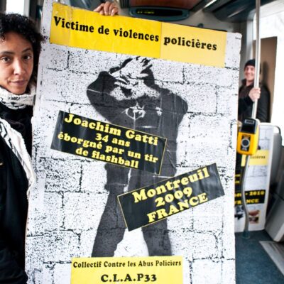 Militante du CLAP portant une pancarte contre les violences policières