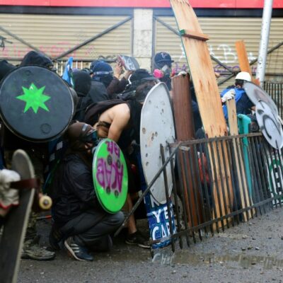 Des manifestants se protègent face aux forces de l'ordre à Santiago, hier vendredi