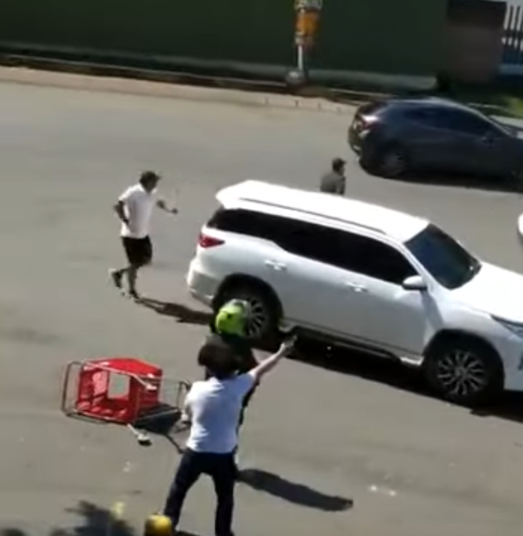 Un milicien ouvrant le feu sur les manifestants à coté d'un policier en uniforme