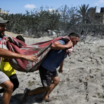 Des Palestiniens évacuent une personne décédée d'un site touché par un bombardement israélien à Khan Younis, dans le sud de la bande de Gaza, le samedi 13 juillet 2024