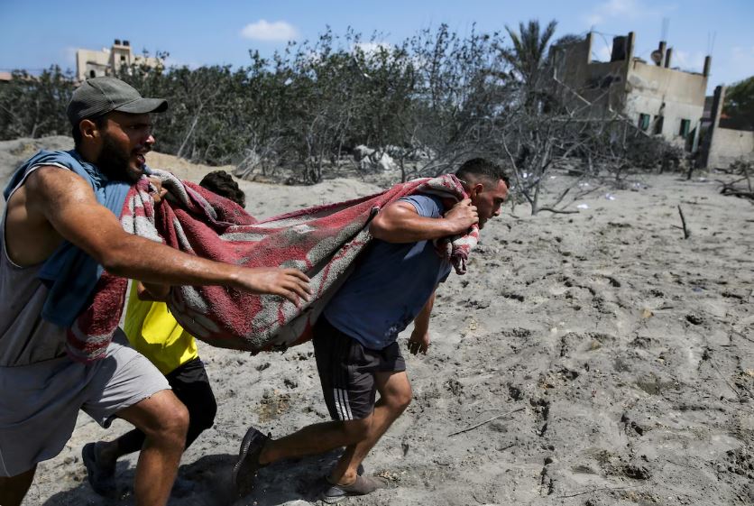 Des Palestiniens évacuent une personne décédée d'un site touché par un bombardement israélien à Khan Younis, dans le sud de la bande de Gaza, le samedi 13 juillet 2024